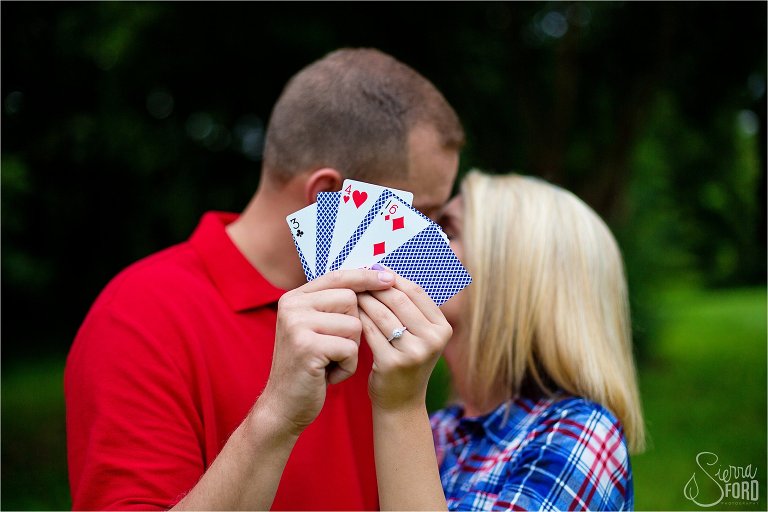 Poker themed engagement session with couple holding up playing cards and kissing