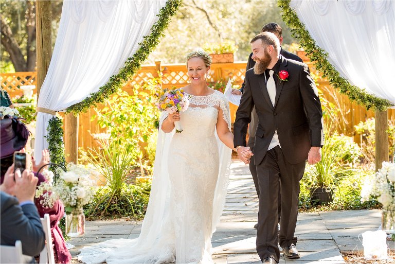 Bride and groom smile walking down aisle after married