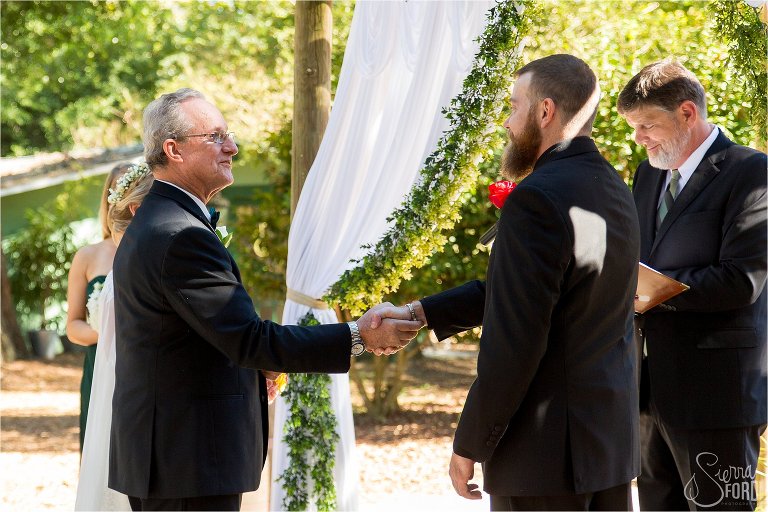 Father of the bride shakes hands with the groom at the altar