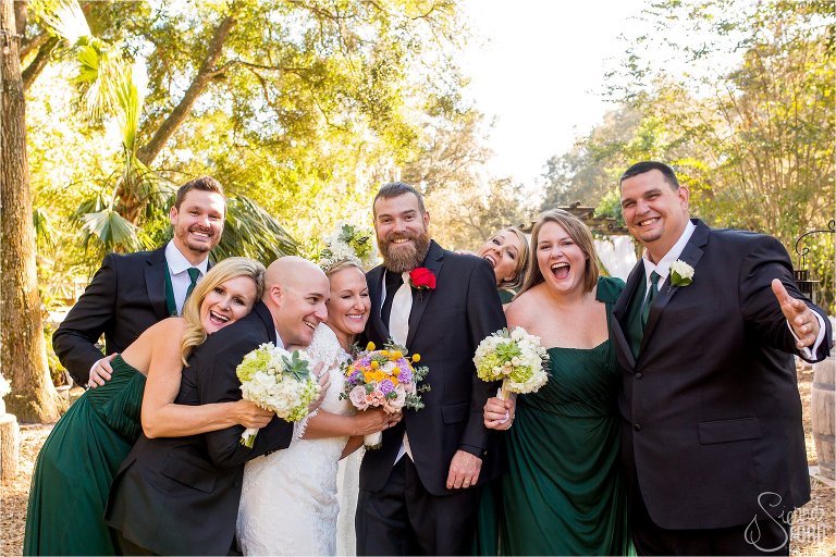 Bridal party hugging and laughin bride and groom