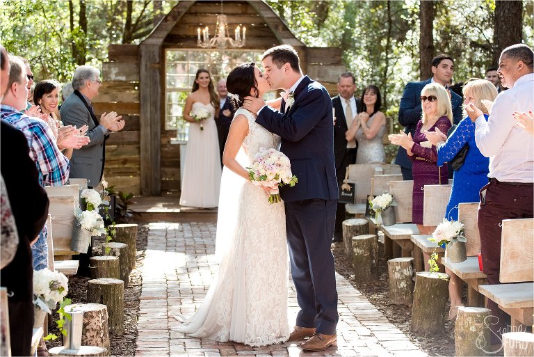 Bride and groom stop in the aisle to share a kiss