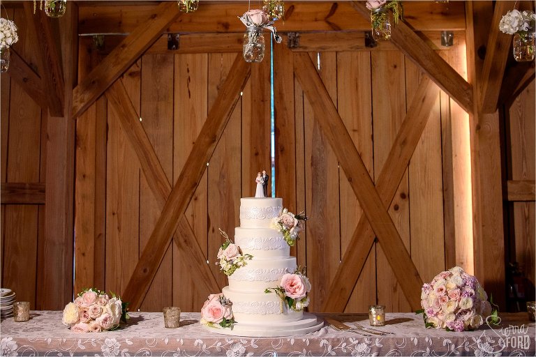 Cake and flowers inside barn reception