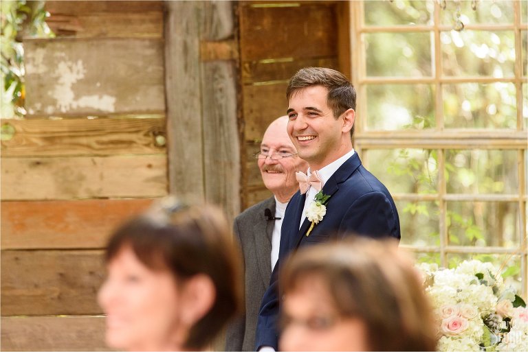 Groom looks down aisle to see bride