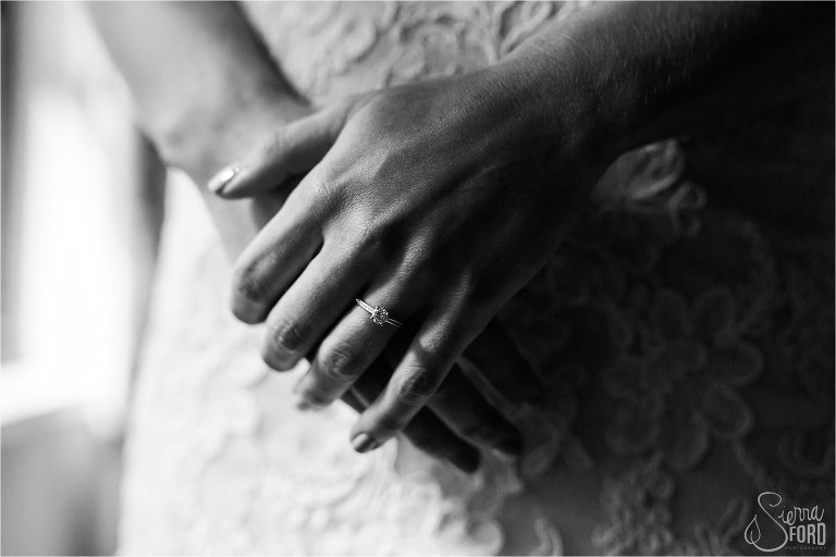 Brides hands clasped while wearing wedding dress and ring