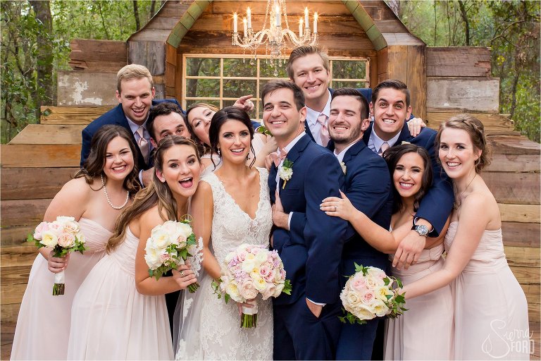 Bridal party hugs bride and groom at altar