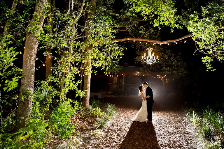 Bride and groom kissing under chandelier after dark