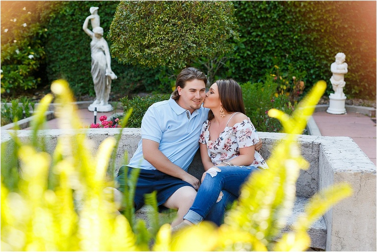 Kissing his cheek as the couple relaxes in the gardens