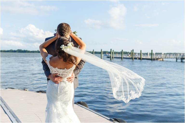 Bride and groom nose to nose on Tavares boat dock with veil blowing in the wind