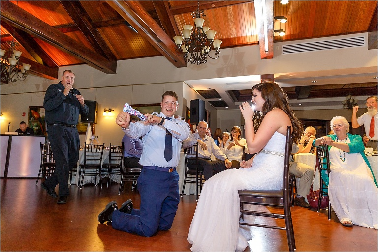 The groom proudly showing off the retrieved garter