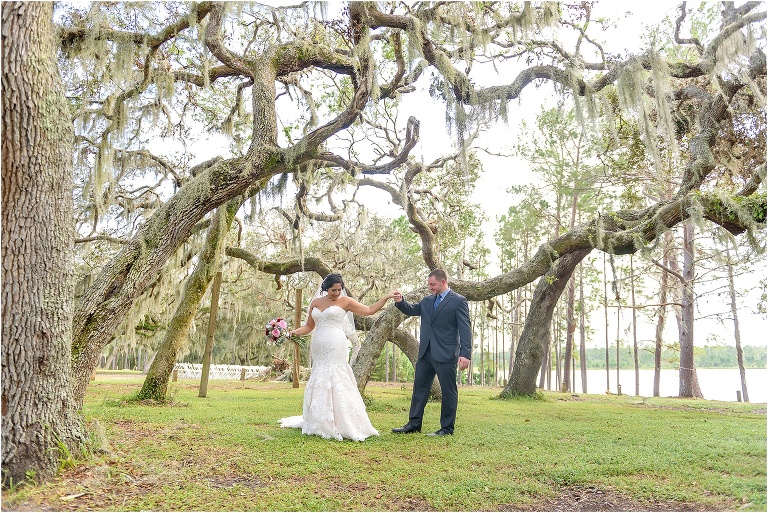 the groom gives the bride a twirl among the Spanish moss