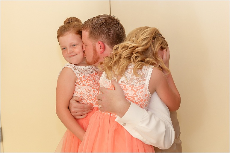 the groom shares a special moment with his daughters before the ceremony