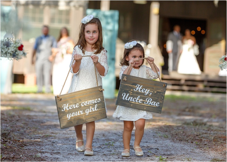 the two cutest flower girls carry signs down the aisle letting their uncle know his bride is coming