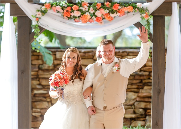 the groom waves to the crowd as he exits with his now wife