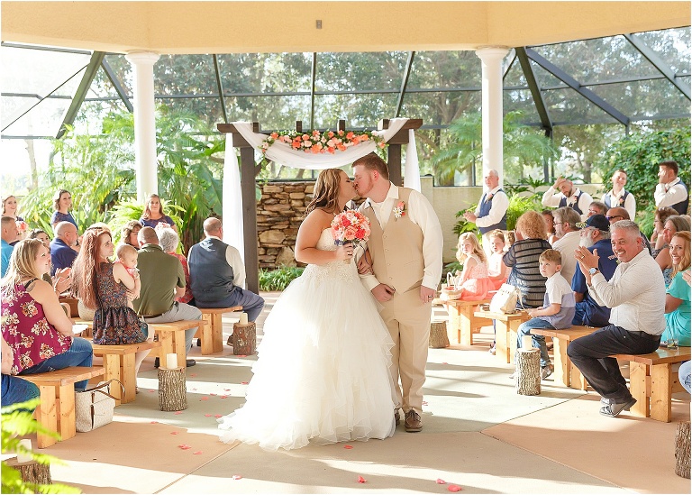 the newlyweds share a kiss as they exit their ceremony