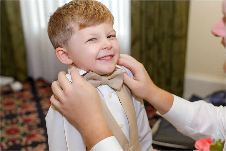 The groom helps his son get dressed for the wedding
