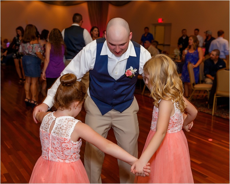 the best man shares a dance with the groom's daughters