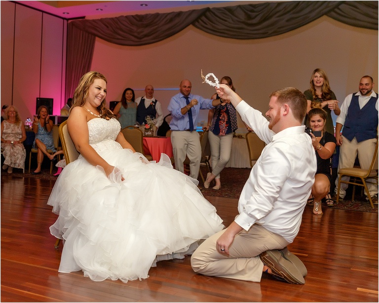 the groom triumphantly waves the garter he retrieved in the air