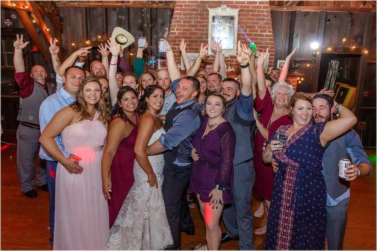 Bride and groom pose with all of their guests on the dance floor at Doe Lake