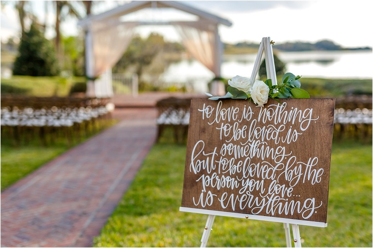 beautiful handmade wooden sign with white cursive text in front of ceremony site