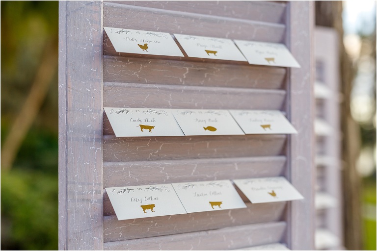 the guests place cards with gold pressed indicators of which dinner option they chose hanging on shutters
