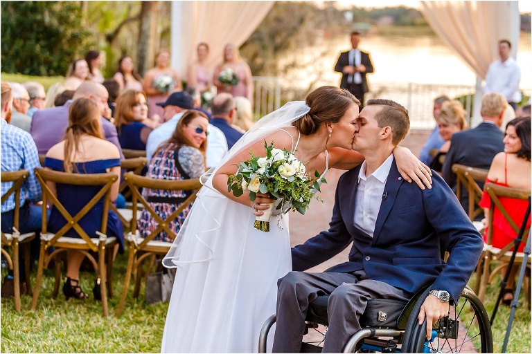 the bride & groom, now husband & wife, kiss at the end of the aisle after their lakeside ceremony at Cypress Grove Estate House