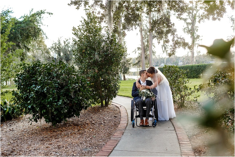 the bride & groom stop to kiss as they walk the lakeside pathway at Cypress Grove Estate House