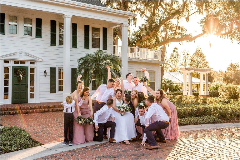 the whole wedding party cheers for the bride & groom in front of the Estate House at Cypress Grove