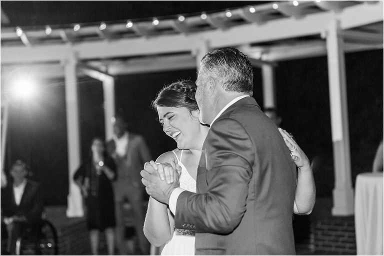the bride smiles as she shares a dance with her father under the market lights at Cypress Grove