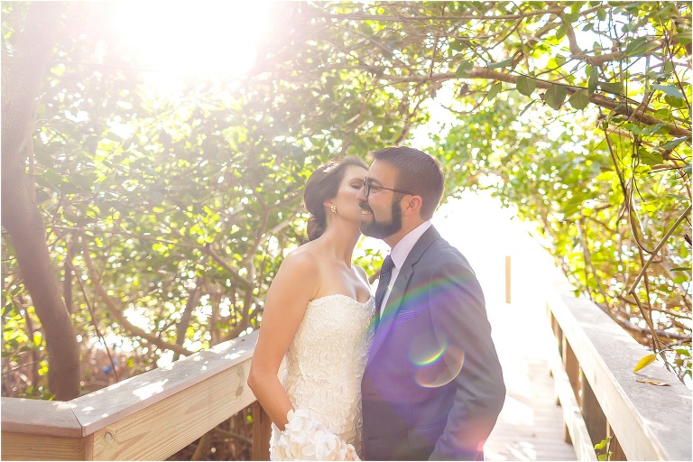 bride kisses groom as the sun rays burst through the banyon trees at Marie Selby Botanical Gardens