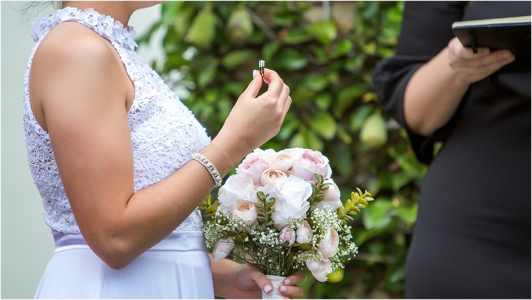 the bride holds up her groom's ring as she prepares to place it on his finger