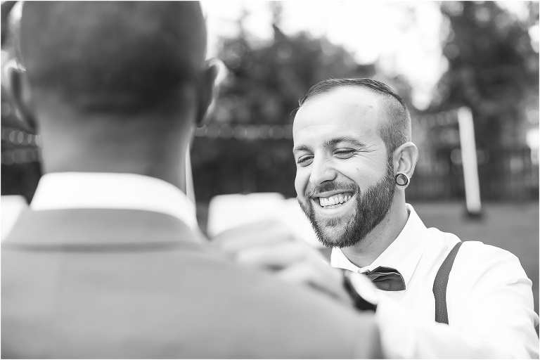 the best man laughs as he tries to fix the groom's tie 