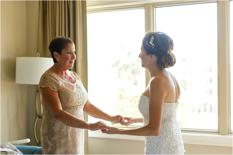the bride and her mother hold hands as her mother takes her in
