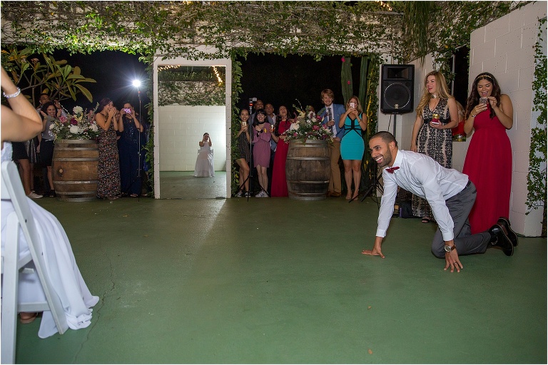 the groom crawls towards his bride to retrieve her garter with his teeth