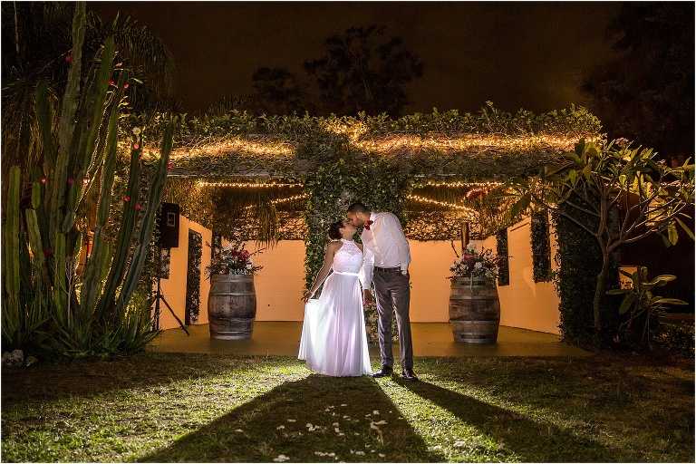 the bride and groom kiss under the twinkle lights at The Acre Orlando