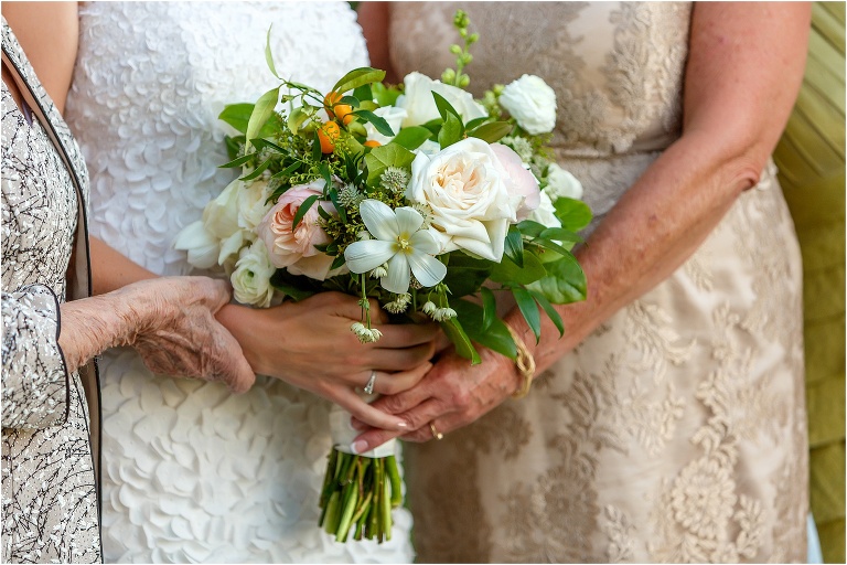 closeup of bride holding her bouquet with her mother and grandmother on either side