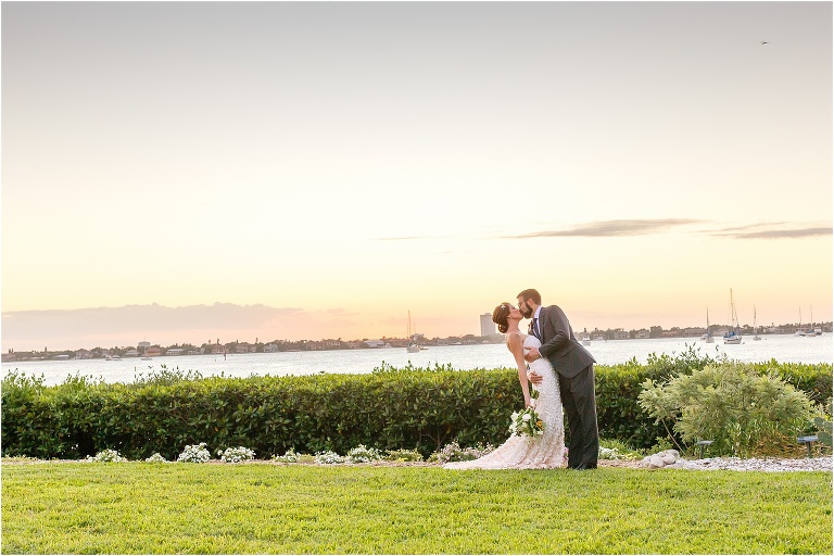 the groom dips the bride for a kiss at sunset