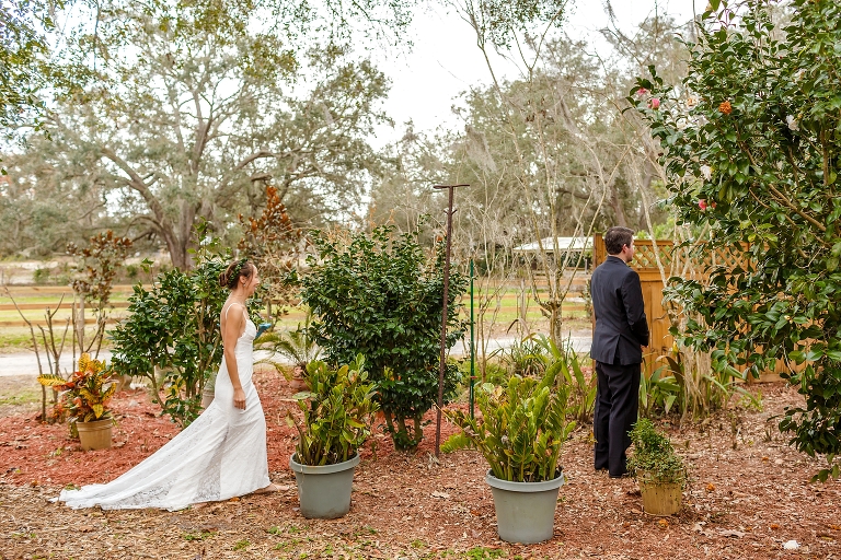the groom patiently waiting to see his bride for the first time among the plants at Harmony Gardens