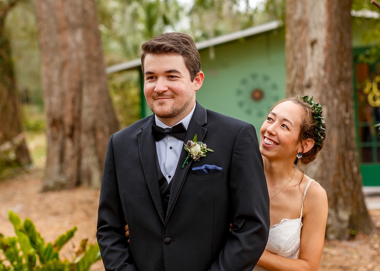 the bride hugs her groom from behind as they see each other for the first time before their DIY garden wedding