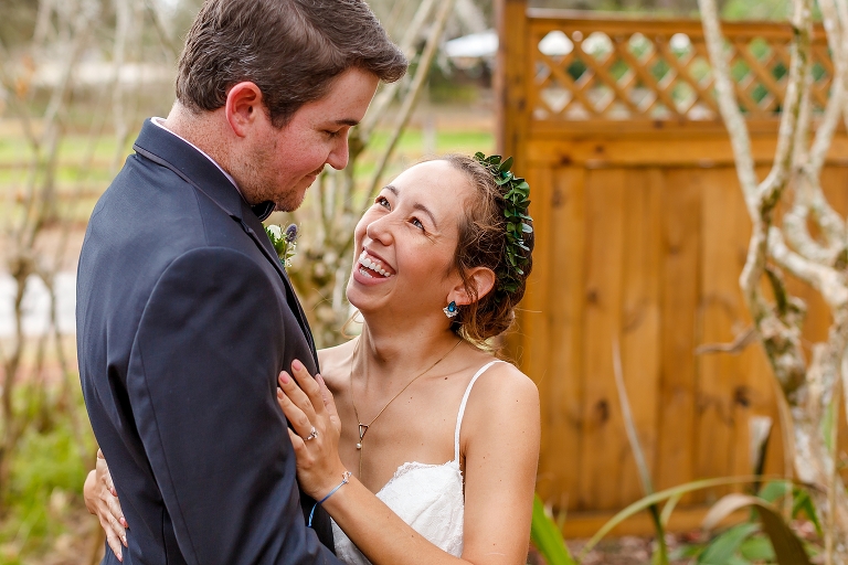 the bride in her floral crown giggles with her groom as he looks lovingly down at her