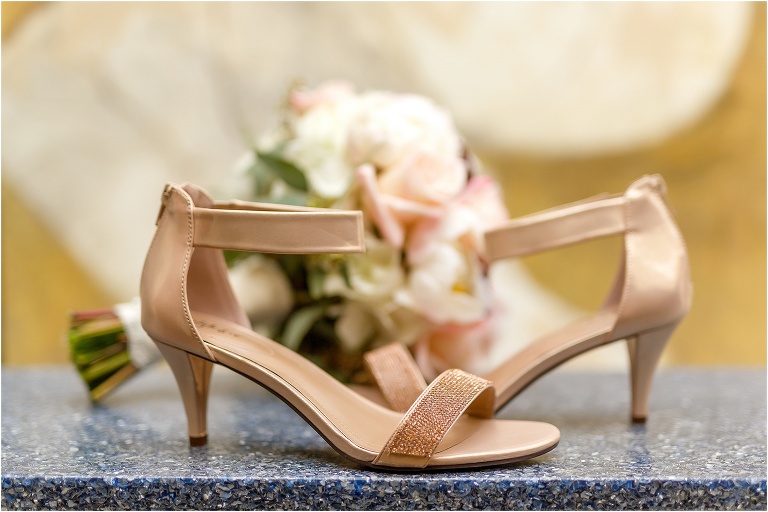 the bride's blush heels sit in front of her Atmosphere Floral bridal bouquet