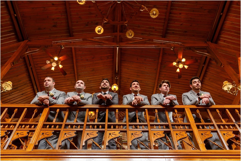 the groom & his groomsmen lean over the balcony at Cheyenne Saloon before the Orchid Garden ceremony
