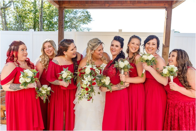 the bride & her bridesmaids laugh together in their JJ's House ruby red bridesmaids dresses