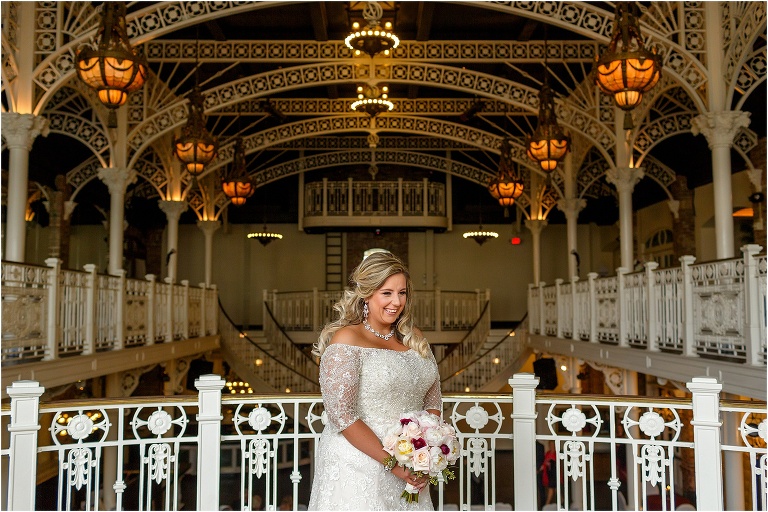 the bride smiles on the top floor of the Orchid Garden Orlando among the historic white columns and banisters