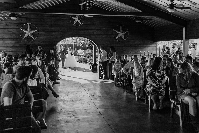 the bride & her father walk down the aisle in the rustic wooden open air chapel at Hidden Barn Venue