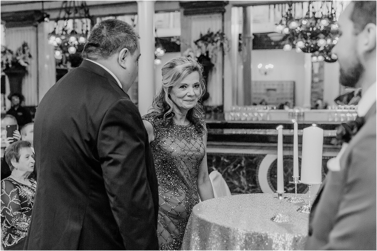 the mother of the bride shares a loving look with her future son-in-law as she walks down the aisle