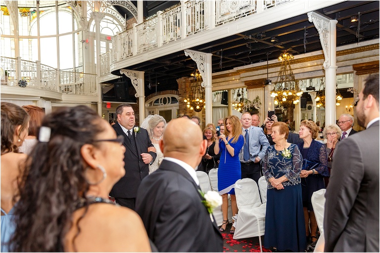 the bride's father escorts her down the rose petal lined aisle at their Orchid Garden Orlando ceremony