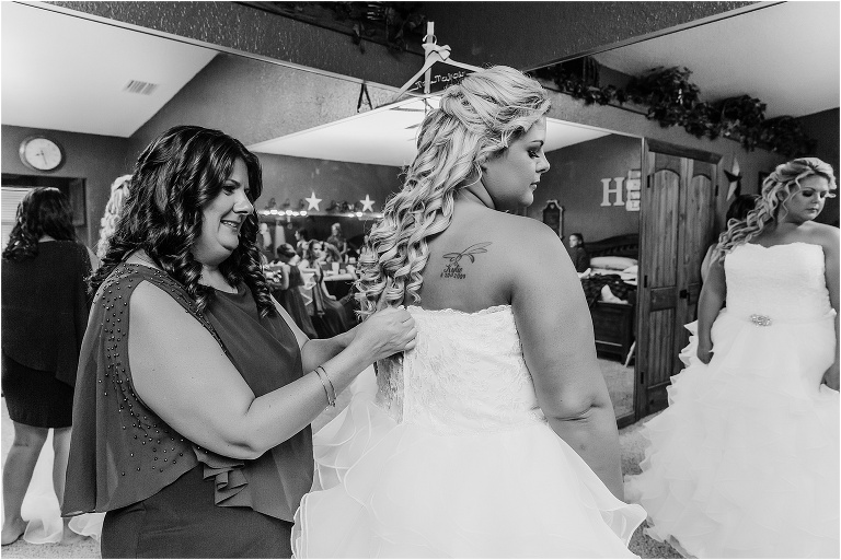 mother of the bride buttons up her daughter's JJ's House wedding gown