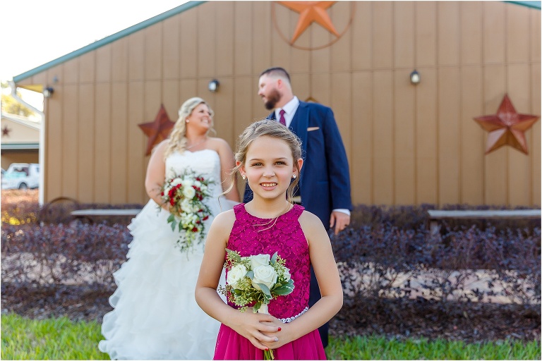 their daughter smiles as the bride & groom look lovingly at each other behind her