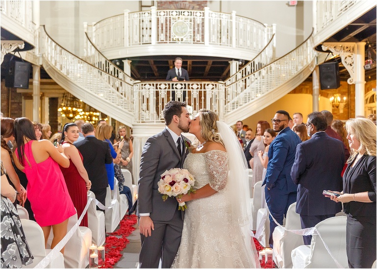 the bride and groom kiss at the end of the aisle after their Orchid Garden at Church Street Station ceremony