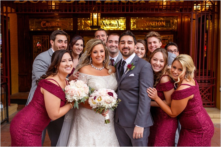 the wedding party rushes the bride and groom for a congratulatory group hug outside historic Church Street Station